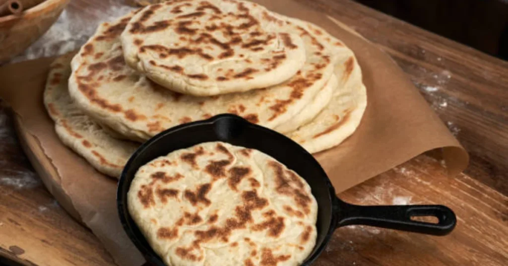 Homemade flatbreads in cast iron skillet showing golden-brown char marks from stovetop cooking, ready to serve