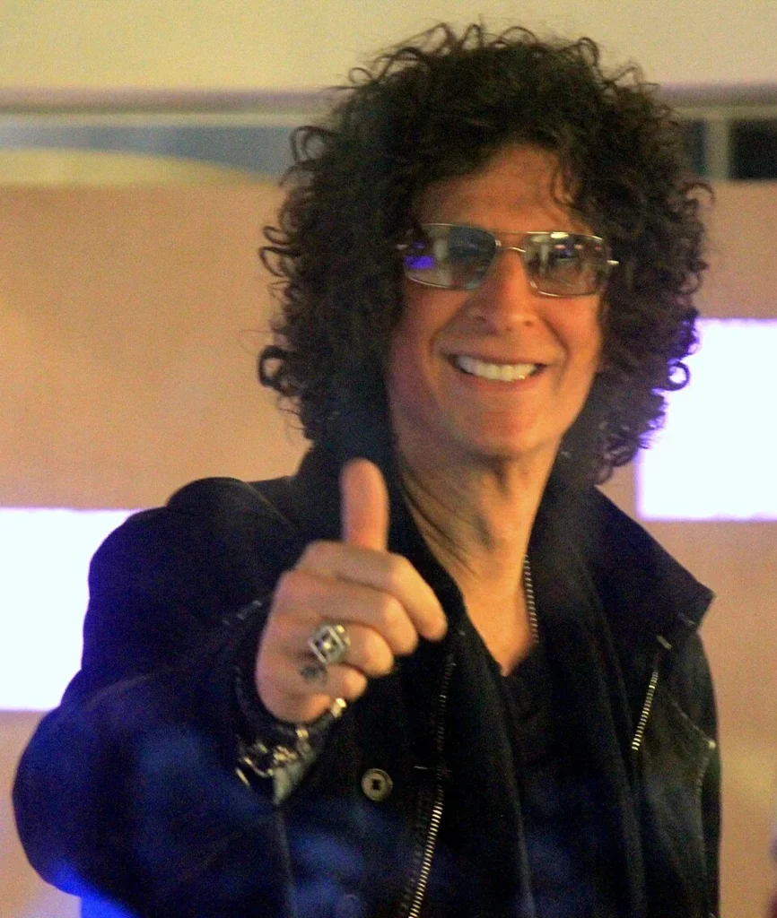 Howard Stern giving thumbs up wearing sunglasses and black jacket