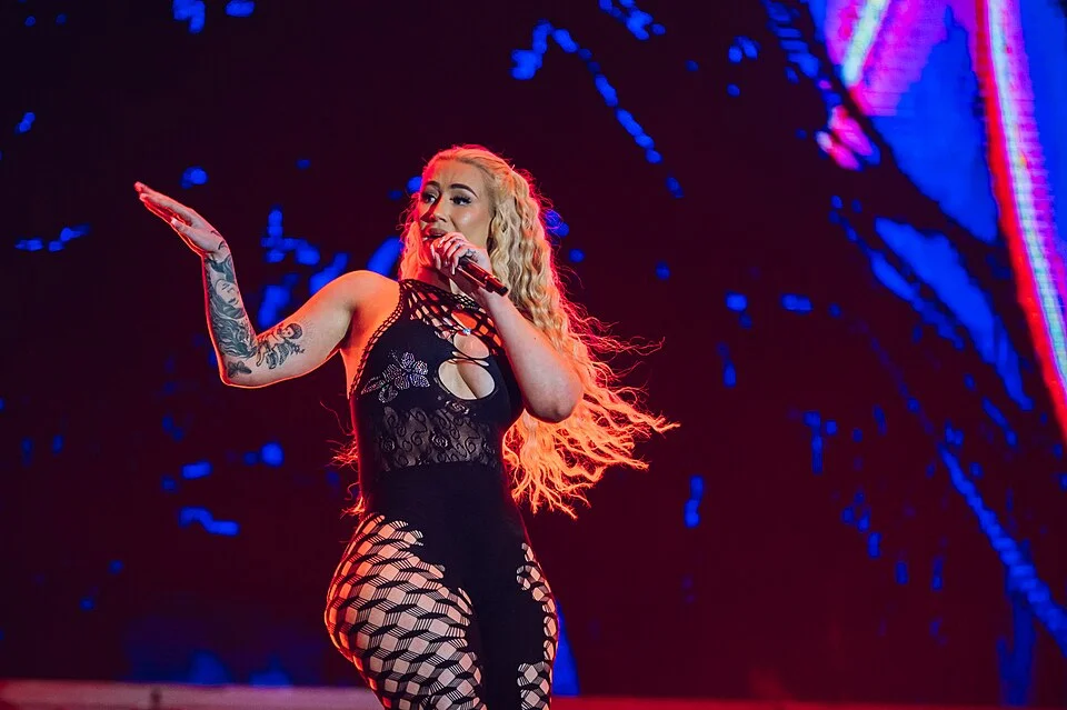Iggy Azalea performing on stage in black cutout outfit with blonde hair