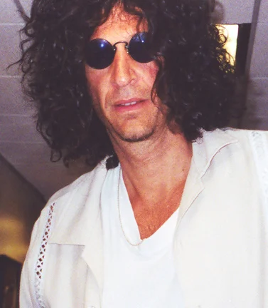 Howard Stern wearing round sunglasses and white shirt in early career photo
