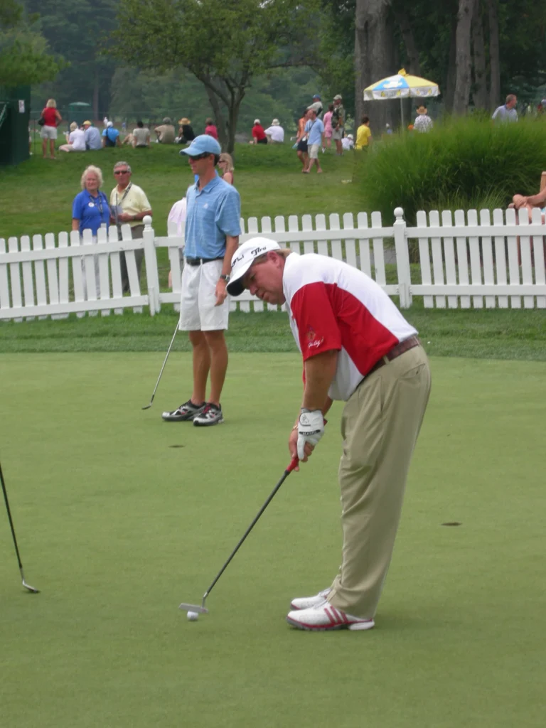 John Daly putting on golf green during PGA tournament with spectators watching