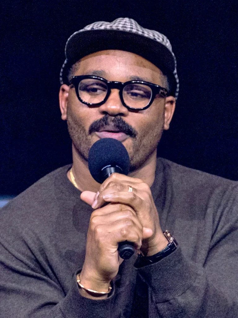 Ryan Coogler wearing glasses and cap speaking at event