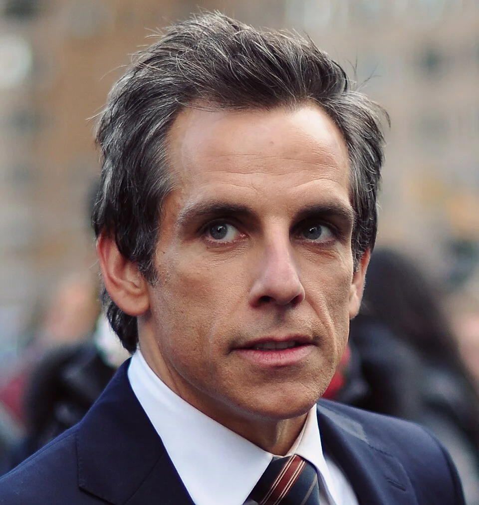 Ben Stiller in a navy suit and striped tie at an outdoor event