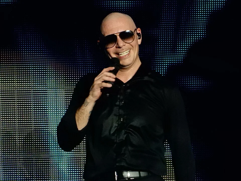 Pitbull smiling on stage with a microphone