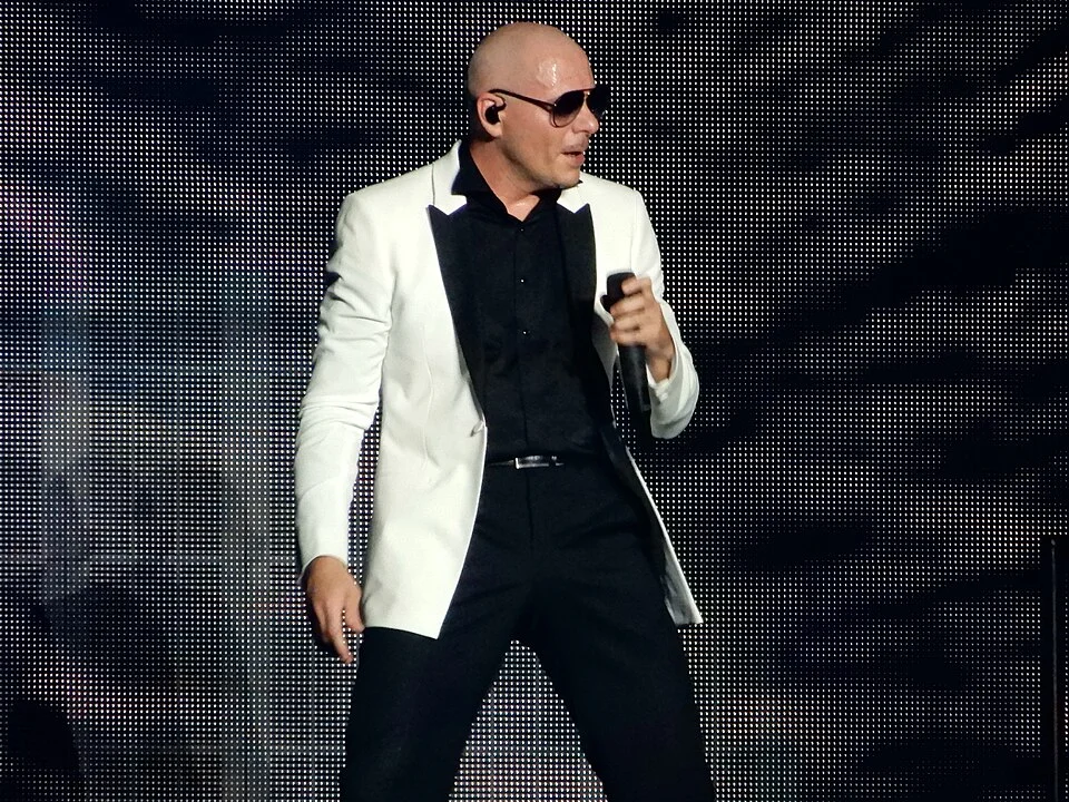 Pitbull performing on stage in a white tuxedo jacket