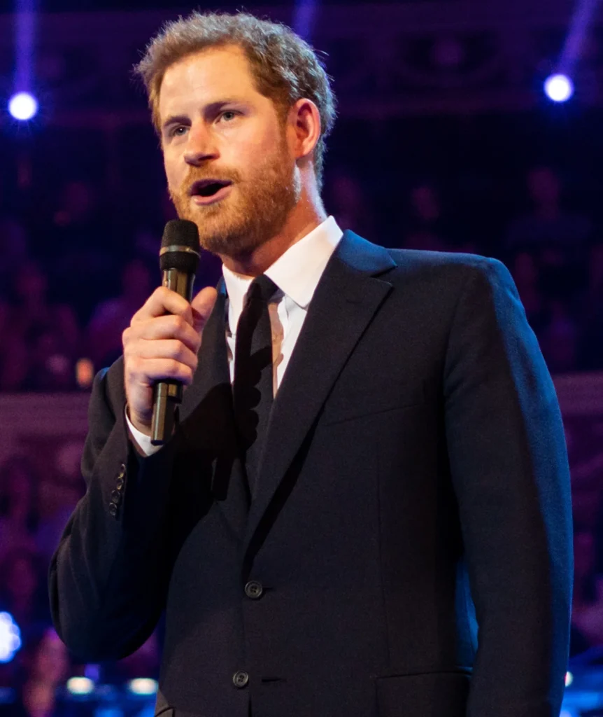 Prince Harry speaking into a microphone on stage at a public event
