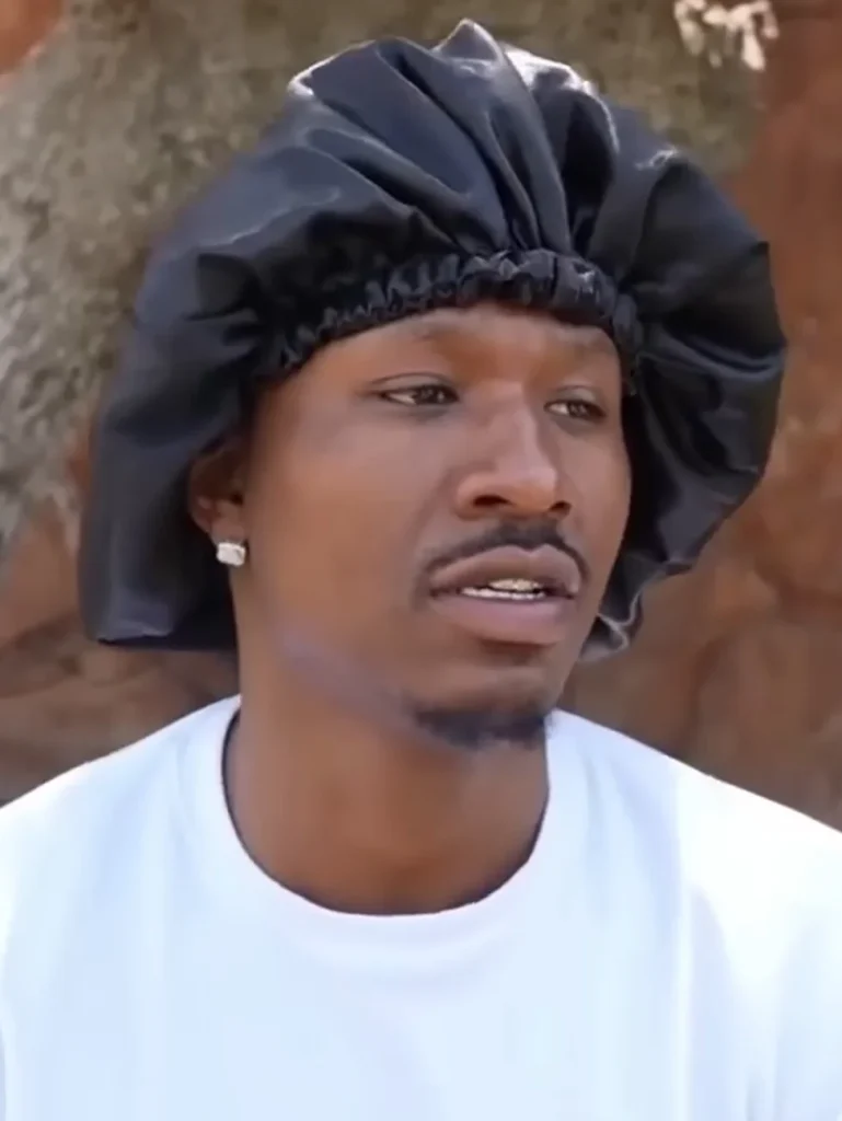 Duke Dennis wearing a black satin bonnet and white t-shirt.