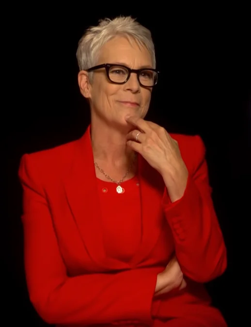 Jamie Lee Curtis wearing glasses and red suit